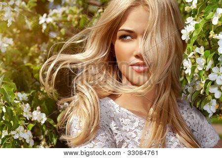 Picture or Photo of Fresh and lovely woman with wind in her hair standing in blossom garden