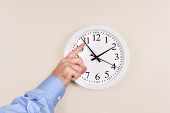 pic of time  - A man changes the time on a clock moving it forward in time spring forward - JPG 