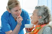 stock photo of home  - senior woman 90 years old being fed by a nurse - JPG 