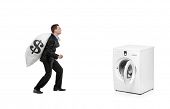 foto of money  - A businessman with money bag on his back going towards a washing machine isolated on white background - JPG 