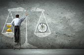 pic of businessmen  - Businessman on ladder pointing at scale picture - JPG 
