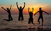 stock photo of people  - silhouette of jumping people on sunset background - JPG 