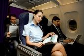 image of business people  - Image of pretty girl reading magazine while handsome man typing next to her in airplane - JPG 