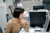 picture of computer  - Single mature Asian woman working in office and looking at computer screen - JPG 