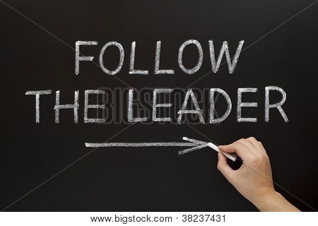 Picture or Photo of Hand showing Follow The Leader written with white chalk on a blackboard