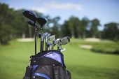 picture of golf  - Blue and black golf bag and clubs against defocused golf course background - JPG 