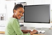 image of computer  - Young Woman Using Computer In Modern Kitchen - JPG 