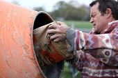 picture of mixer  - Man putting cement in a mixer - JPG 
