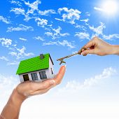 stock photo of house  - Human hand against blue sky background and house - JPG 