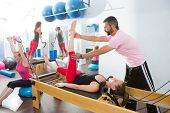 stock photo of fitness  - Pilates aerobic personal trainer instructor man in cadillac fitness woman exercise - JPG 