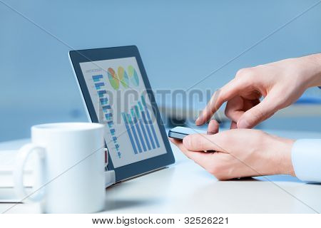 Picture or Photo of Businessman uses the apple iphone and apple ipad  to work successfully.