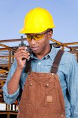 foto of construction worker  - Handsome black man construction worker talking on a walkie talkie - JPG 