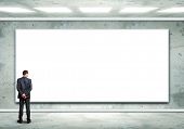 pic of business concept  - Business person standing near a white blank  billboard - JPG 