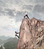 picture of cord  - Businessman on the top of a rock helping an other businessman to climb it - JPG 