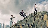 stock photo of group  - Image of three businesspeople pulling rope atop of mountain - JPG 