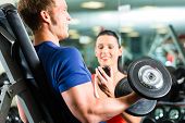 picture of fitness  - Man or Bodybuilder with his personal fitness trainer in the gym exercising sport with dumbbells - JPG 
