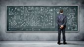 image of business  - Business person standing against the blackboard with a lot of data written on it - JPG 