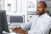 stock photo of computer  - Casual afro businessman sitting at office desk - JPG 