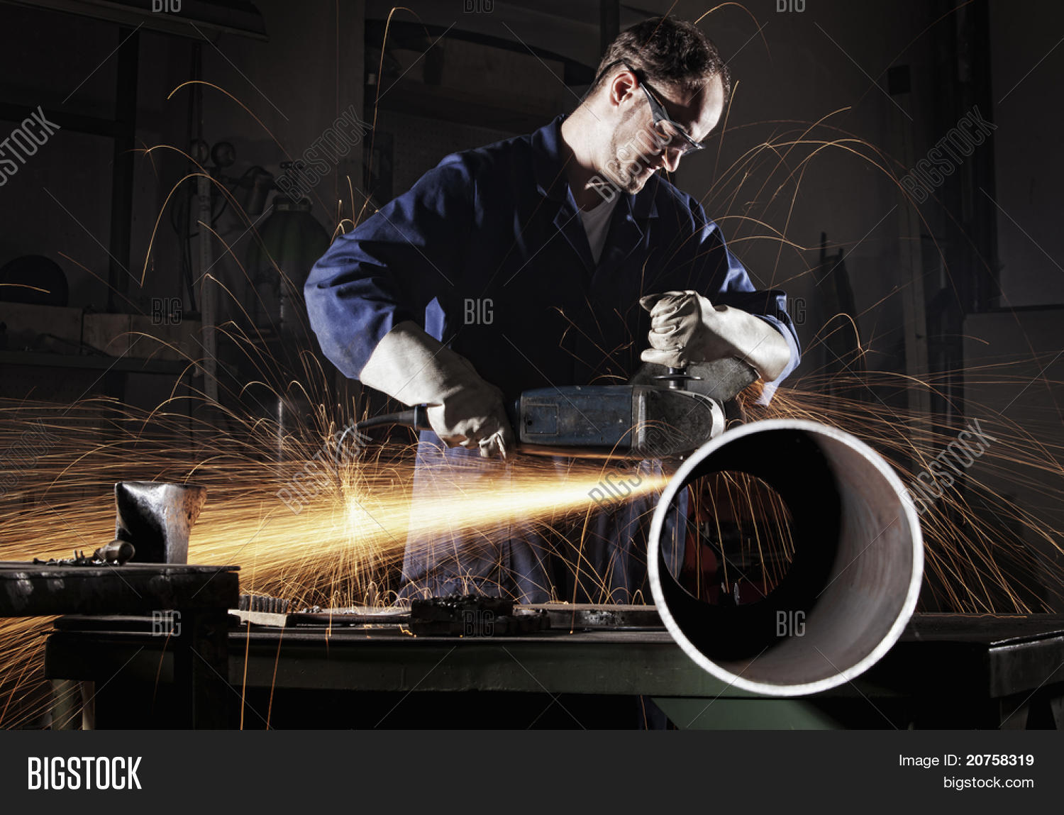 Heavy industry worker cutting steel pipe with angle grinder in