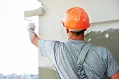 foto of industrial  - Young painting facade builder worker with roller at thermal insulation works - JPG 