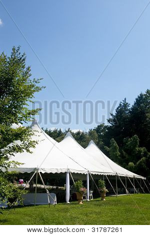 Picture or Photo of A large white wedding tent set up for an outdoor function or banquet