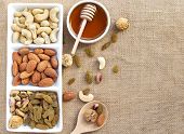 Dried fruits and variety of nuts in a dish with honey in a bowl on the wooden table, such as figs, almonds, raisins, cashews, and pistachio. with copy space for your text.