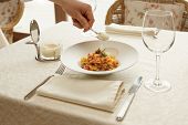 Waiter is adding grated cheese to pasta in expensive restaurant