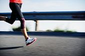 foto of fitness  - Athlete runner motion blur running on road focus on shoe - JPG 