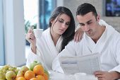 picture of newspaper  - young family couple read newspaper at kitchen in morning with  fresh breakfast  fruits food and coffee drink on table - JPG 