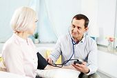 picture of pressure  - Portrait of mature man measuring blood pressure of his wife and looking at her - JPG 