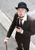 foto of yesterday  - High Angle View Of Old Fashioned Gentleman In Suit With Walking Cane And Bowler Hat Smoking Pipe On The Hazy Streets Of Yesterday - JPG 