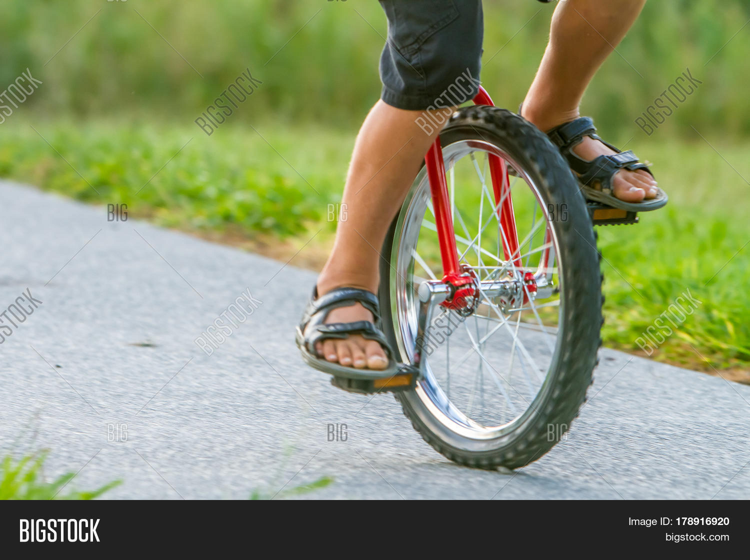 outdoor portrait of young boy riding a unicycle (one wheel bike) on