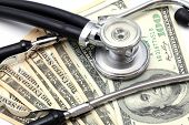 stock photo of currency  - Stethoscope on Money Dollar Cash Currency Banknote Background Using for Healthy Financial and Insurance Concept - JPG 