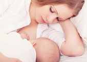 stock photo of tranquil  - mother feeding breast her baby in the bed - JPG 