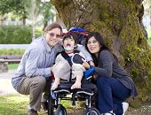 picture of cerebral  - Happy disabled child in wheelchair surrounded by parents outdoors - JPG 