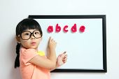 stock photo of toddlers  - School girl wears a big spectacles posing next to a white board - JPG 