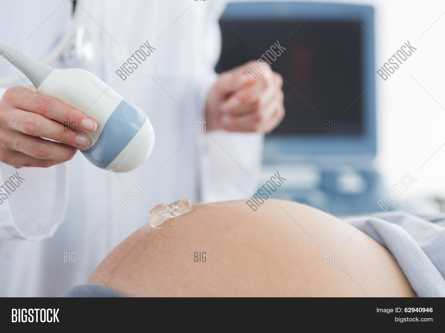 Midsection of doctor applying gel on belly of pregnant woman for ultrasound in clinic Stock