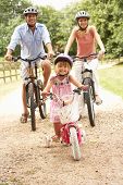 pic of family  - Family Cycling In Countryside Wearing Safety Helmets - JPG 
