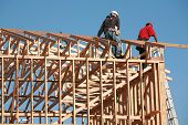 stock photo of construction  - unidentifiable construction workers work on framing a building - JPG 