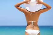 pic of holidays  - Travel woman on beach enjoying blue sea and sky wearing white beach sun hat and bikini - JPG 
