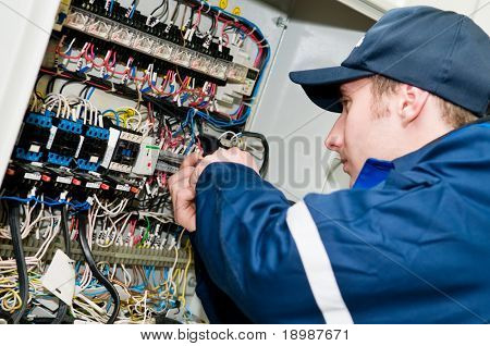 Picture or Photo of One electrician working on a industrial panel mounting, assembling, adjusting new voltage wiring