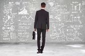 stock photo of man  - back view of a business man holding a briefcase and looking at some charts  - JPG 