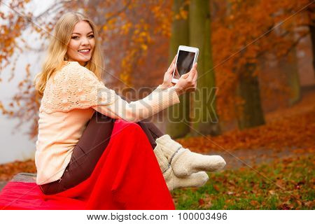 Woman In Autumn Park Using Tablet