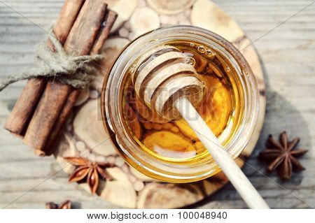 Golden honey with honeystick. cinnamon and anise stars on wooden table