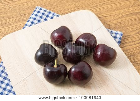 Group Of Red Plums On A Wooden Cutting Board