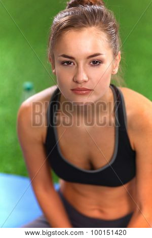 Beautiful young woman relaxing after exerscises on the grass 