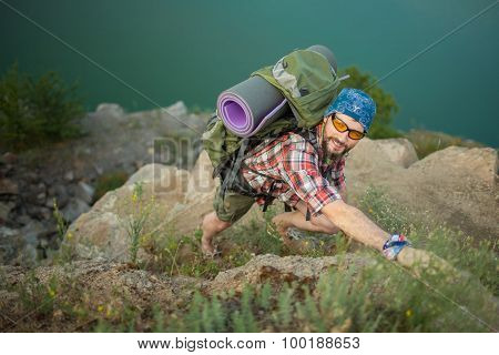 Young caucasian man with backpack climbing the rock