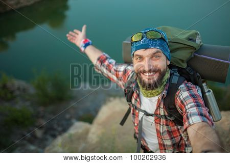 Young caucasian man with backpack standing on the top of hill