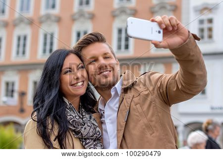 a young couple making a self portrait with a mobile phone. selfies are in.