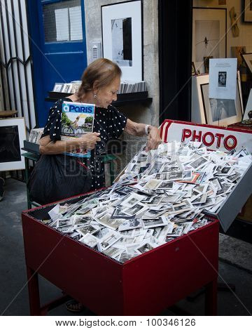Senior woman looking at old photos at an outdoor market in paris